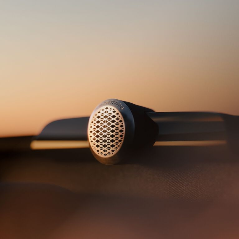 Small silver circular Bowers & Wilkins speaker with orange gradient background